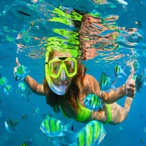 mujer haciendo snorkel en el mar de Cozumel rodeada de brillantes peces amarillos