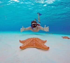 hombre haciendo snorkel posando con una estrella de mar