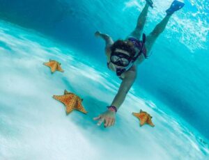 mujer haciendo snorkel en el cielo tocando la arena blanca