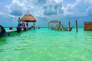 laguna super cristalina y en tonos azules y verdes en la laguna de bacalar con un puente y hamacas en medio del agua