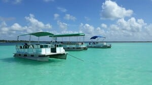 tres diferentes pontones encima de la laguna de bacalar con el cielo con nubes y agua cristalina y en tonos verdosos y azules